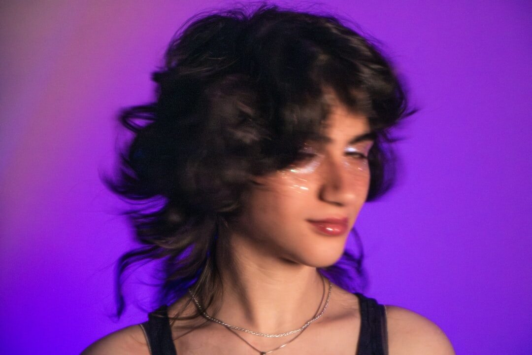 Studio portrait of a young Uruguayan woman with curly hair against a purple background
