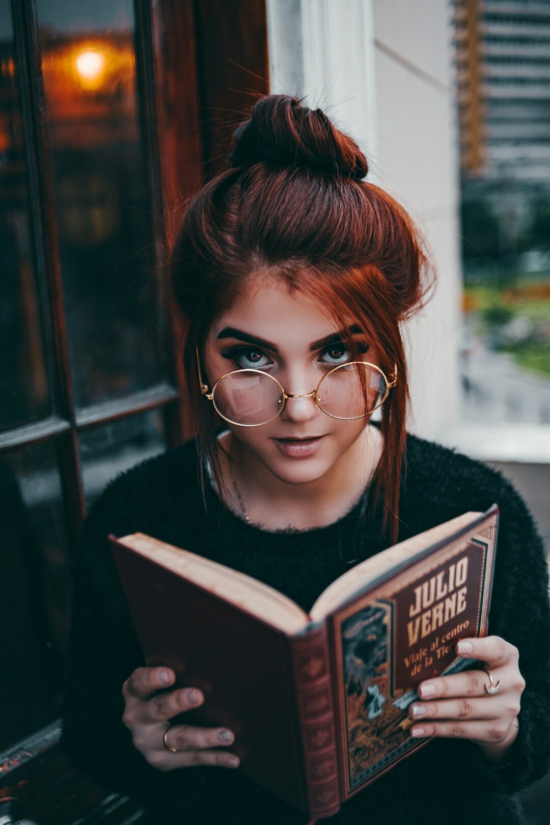 Close-up portrait of a young Uruguayan woman wearing glasses while reading a book