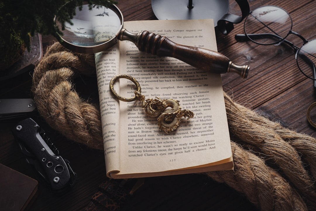 Overhead view of a wooden desk with an open mystery novel and a magnifying glass